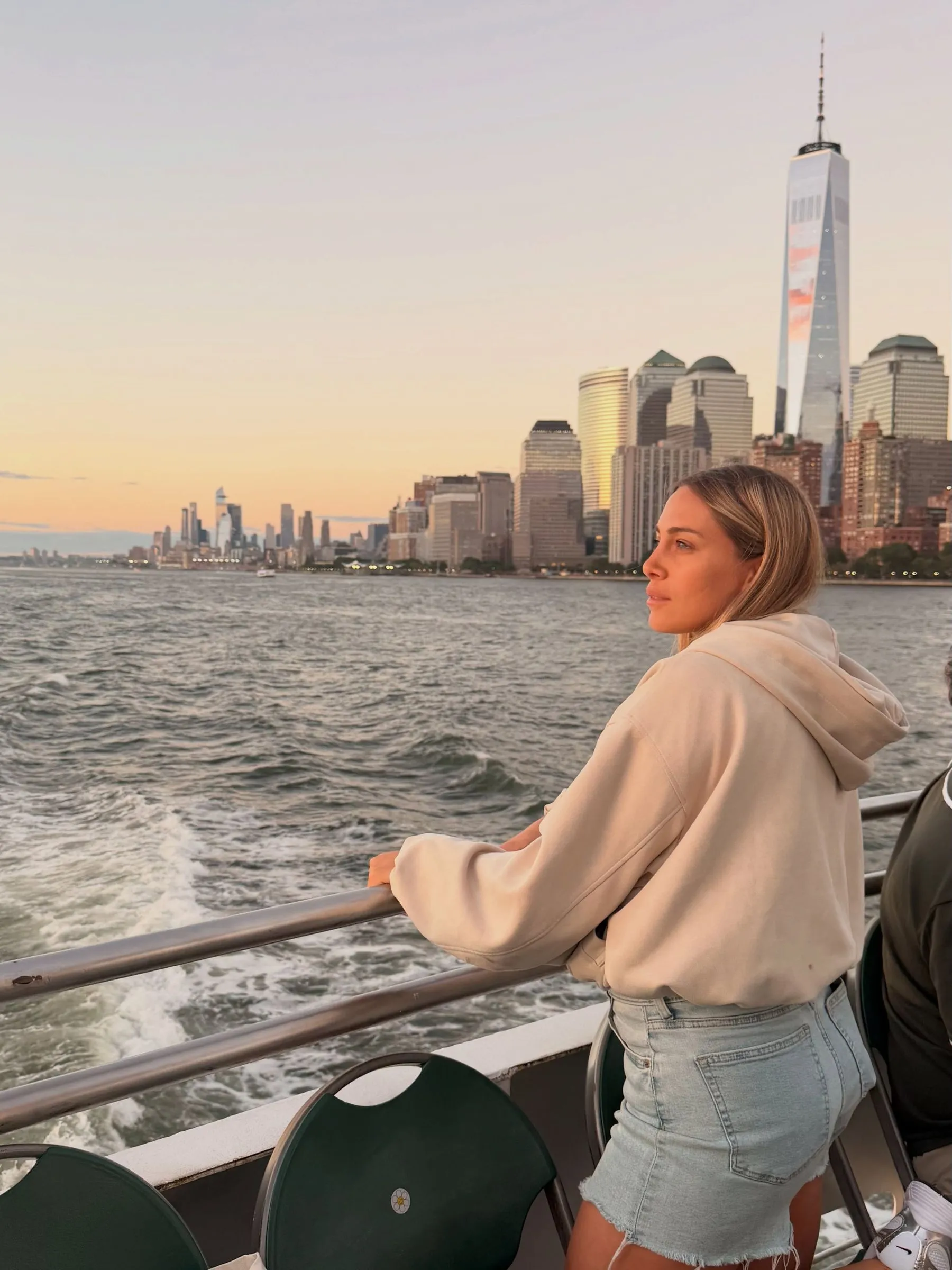 Ailu Greco en un ferry frente al skyline de Manhattan al atardecer
