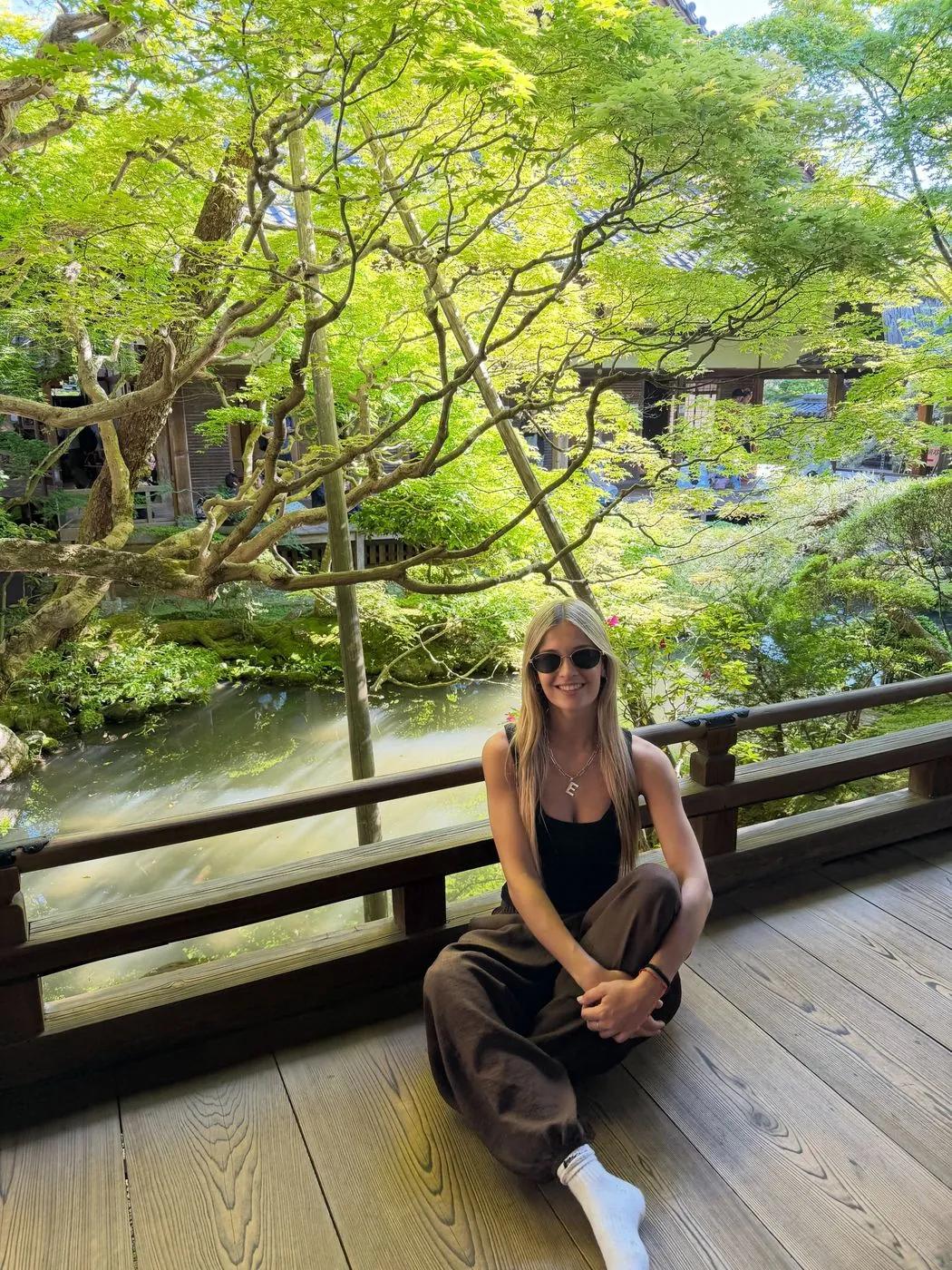Emi en un mirador de madera entre árboles, en Kioto