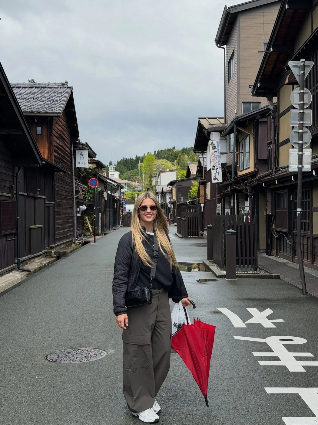 Emi con un paraguas rojo en una calle de Takayama