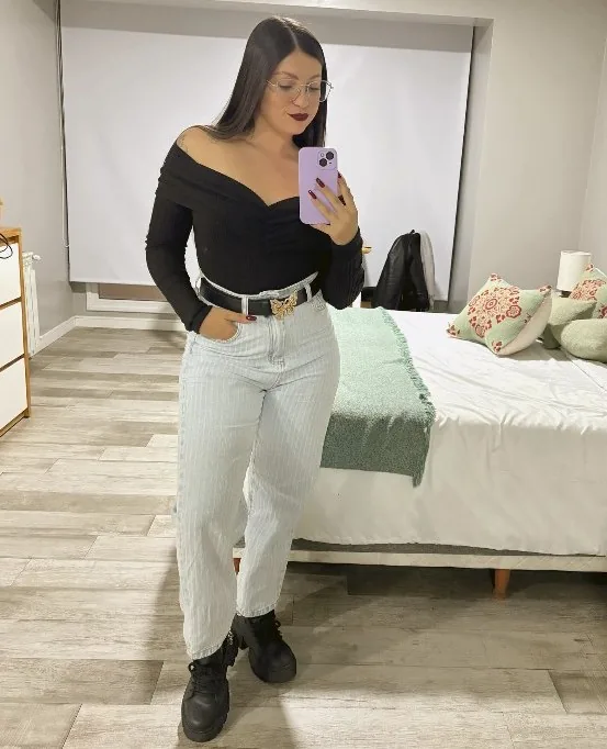 Juli frente a la cámara en su cuarto, con ropa oscura y jeans claros