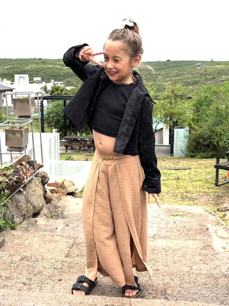 Alma posando con campera negra, top y pantalón ancho beige en las sierras