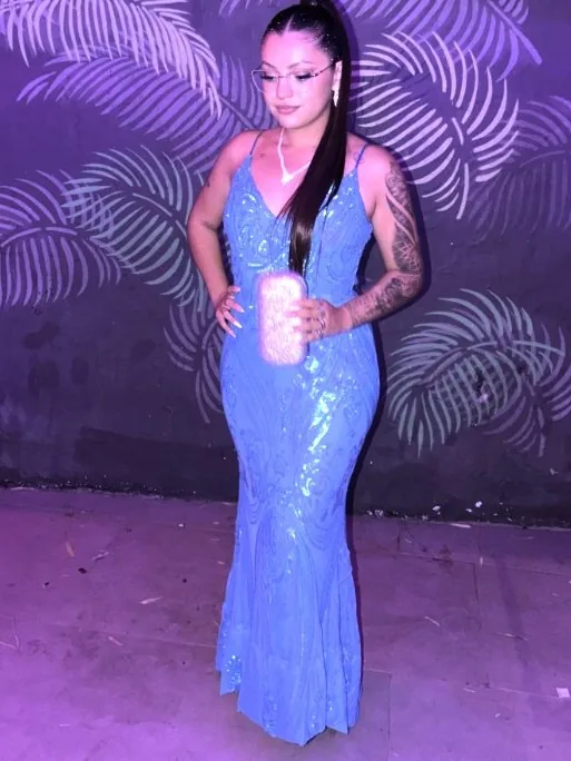 Juli con un vestido de gala azul frente a un fondo violeta