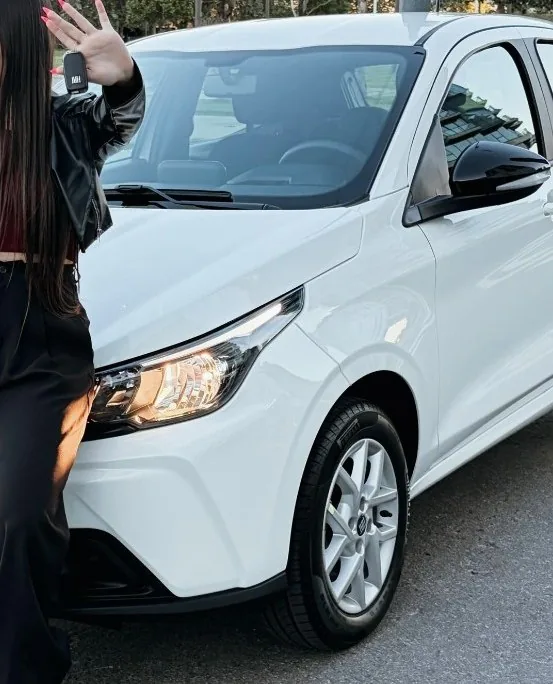 Juli junto a su auto blanco