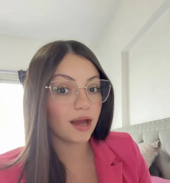 Juli con blazer rosa y anteojos, mirando a cámara, lista para grabar